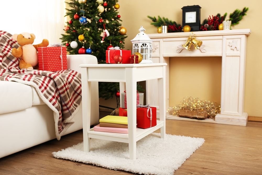 Espacio navideño acogedor con una mesa auxiliar decorada con regalos y una linterna, un árbol festivo y una chimenea adornada. La combinación de elementos tradicionales y modernos crea un ambiente cálido y festivo para la Navidad 2024.